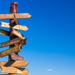 Signpost with blank arrows on blue sky background